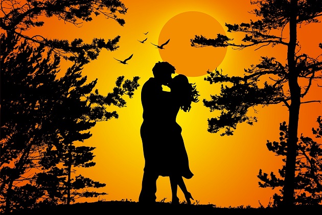 Siluete îndrăgostiți care se sărută îmbrățișați într-o pădure, la lumina lunii pline.