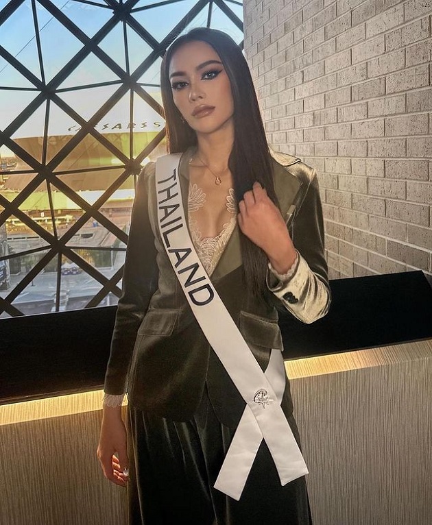 Miss Thailanda într-un compleu kaki de catifea, purtând banderola cu numele țării