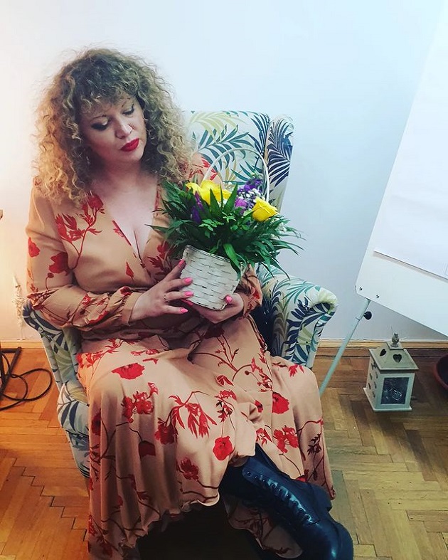 Oana Lis într-o rochie înflorată, ținând în mână un coș cu flori colorate