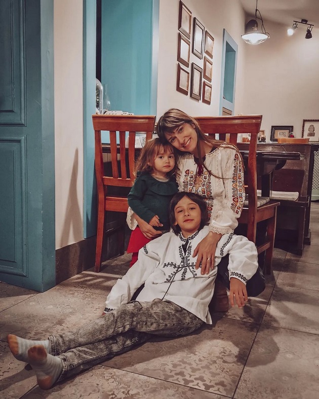 Dana Rogoz îmbrăcată în ie, stând pe jos în bucătărie, alături de copiii ei