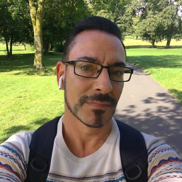Timothy Welch pe o alee din parc, purtând ochelari, ghiozdan în spate și căști în urechi