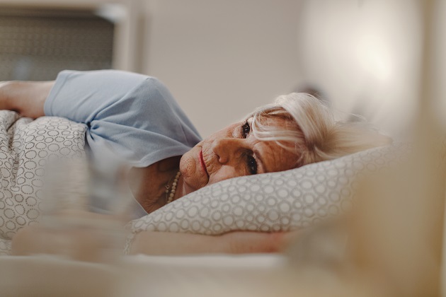 Femeie în vârstă care suferă de insomnie și se uită pe tavan