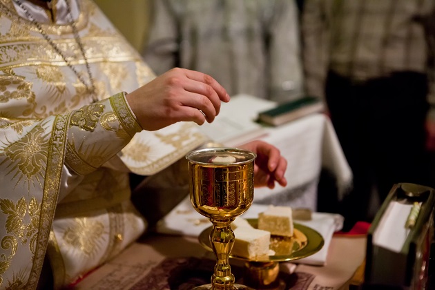 Preot care pregătește painea și vinul pentru Sfânta Taină a Împărtășaniei
