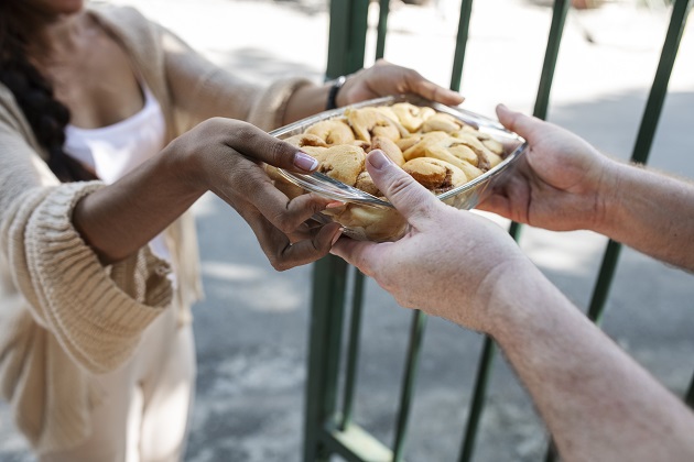 Femeie care oferă un bol cu biscuiți unui bărbat aflat lângă o poartă