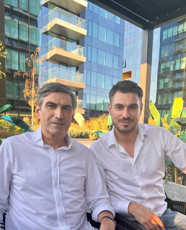 Victor Pițurcă și Alex Pițurcă, îmbrăcați în cămăși albe, în timp ce stau împreună la o terasă.