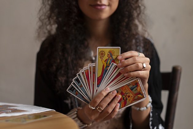 Femeie brunetă cu păr creț, în timp ce extrage o carte din pachetul de cărți de Tarot