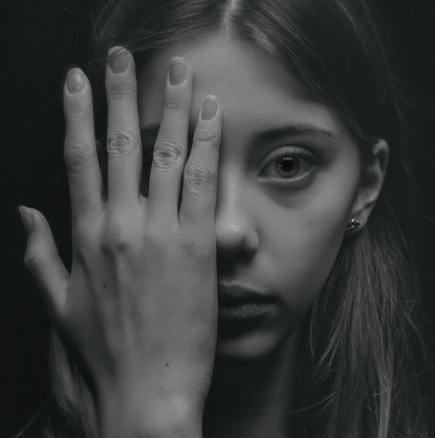 Imagine alb negru cu o fată care îți acoperă jumătate de față cu palma
