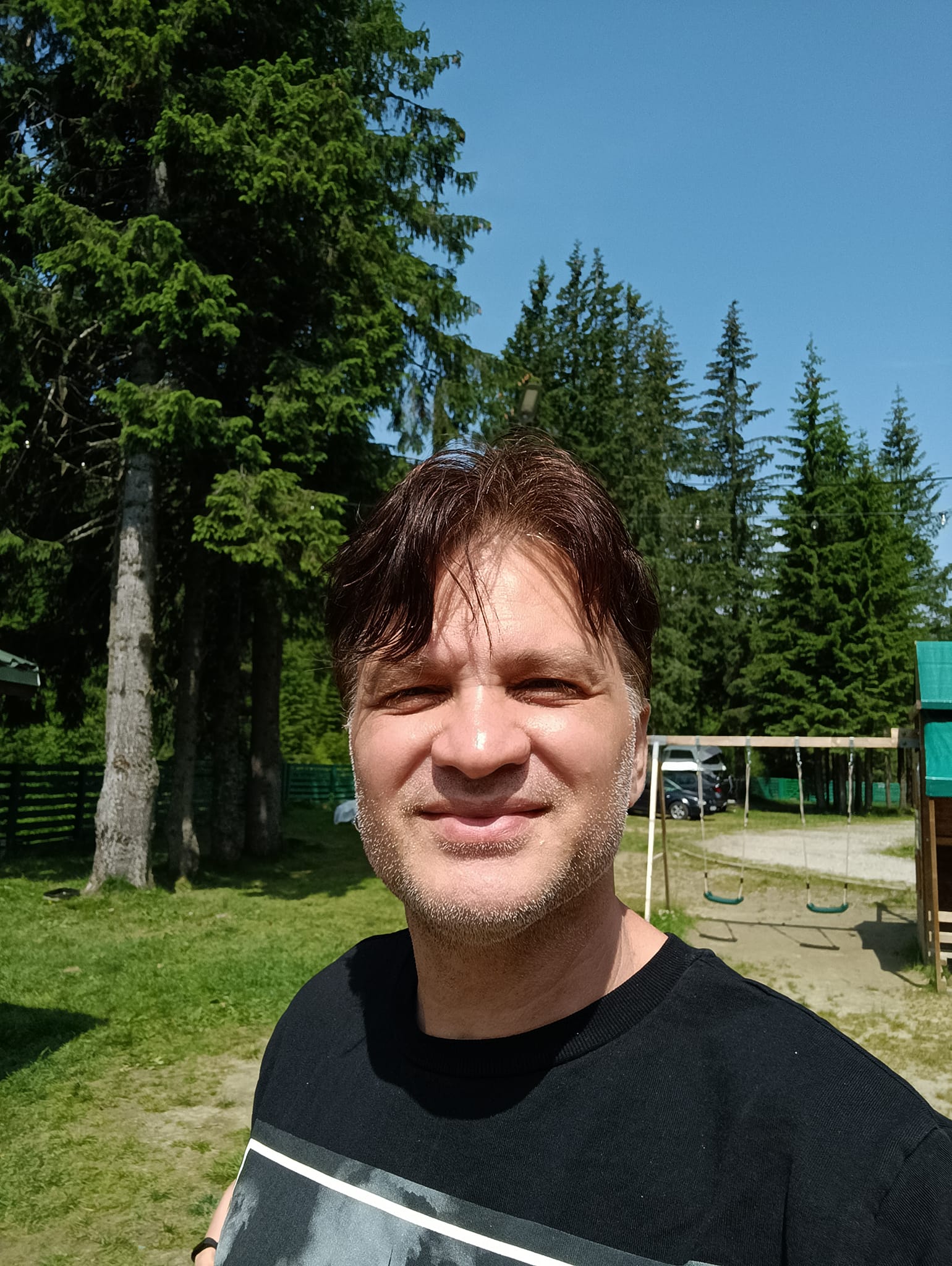 Mihai Onilă într-o vacanță la munte, stând în razele soarelui, îmbrăcat într-un tricou negru