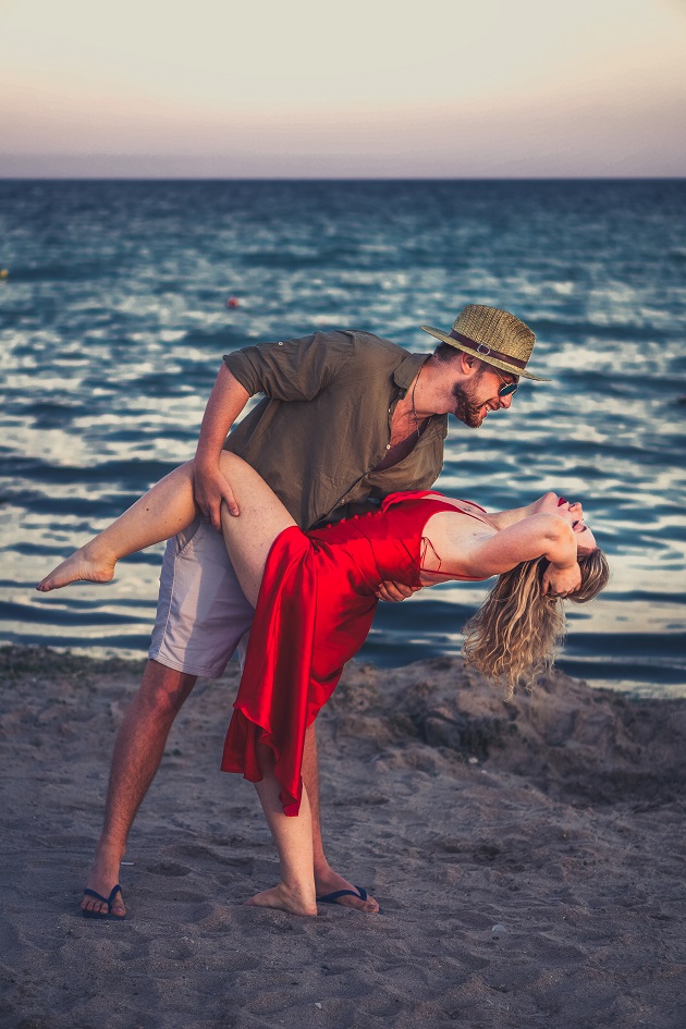 Cuplu care dansează pe plajă la apus