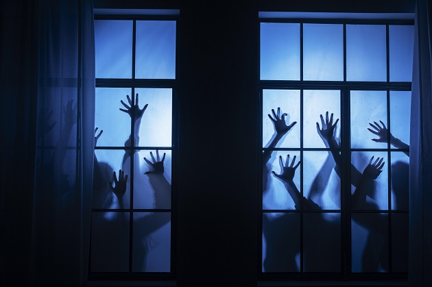 Siluete de oameni cu mâinile ridicate, în timp ce stau noaptea la fereastră