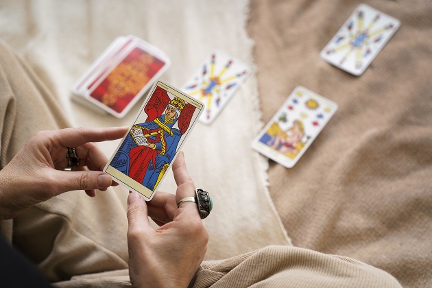 Femeie care ține în mâini cartea de Tarot Marea Preoteasă