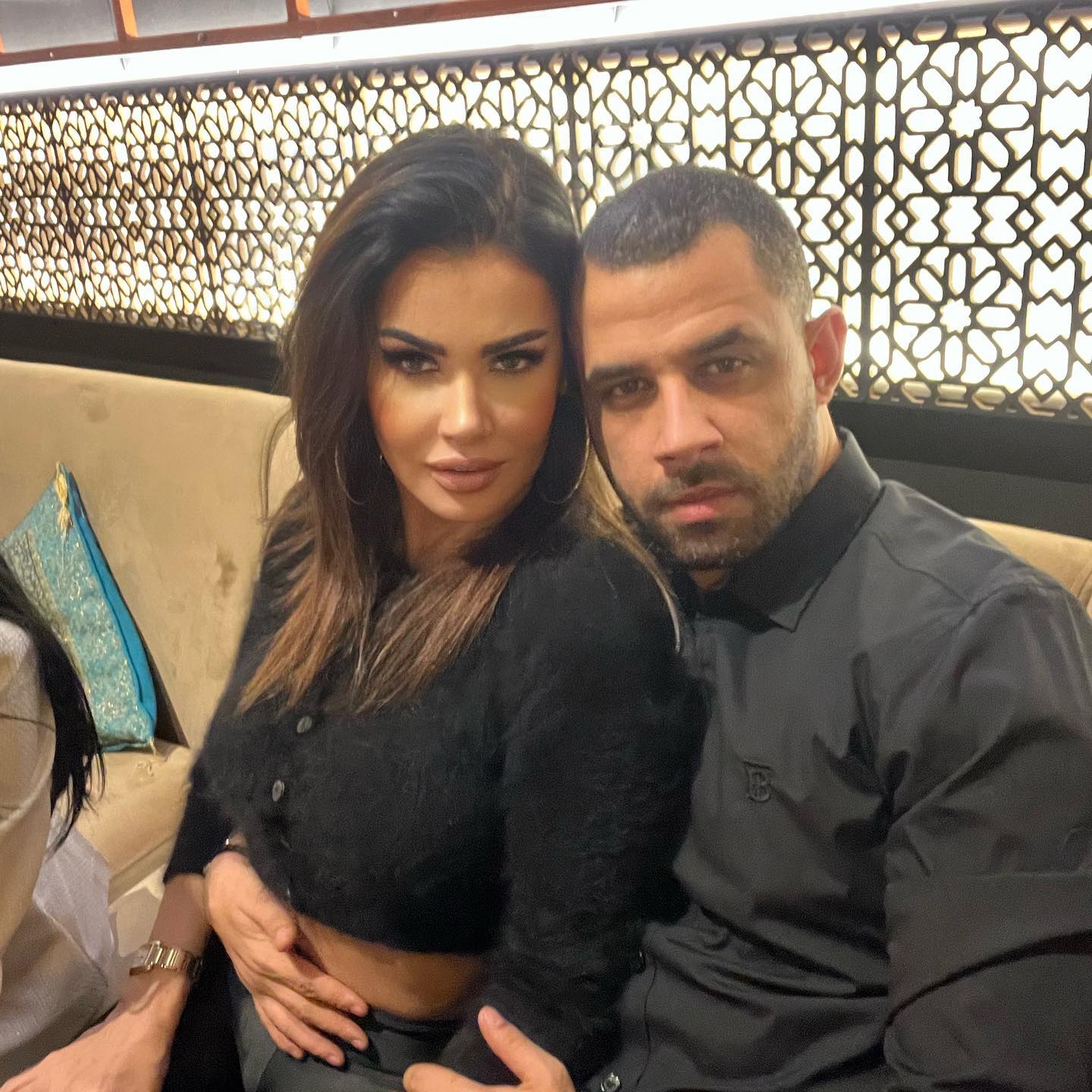 Alex Ashraf o ține în brațe pe Oana Zăvoranu pe canapeaua dintr-un restaurant, în timp ce sunt îmbrăcați asortat