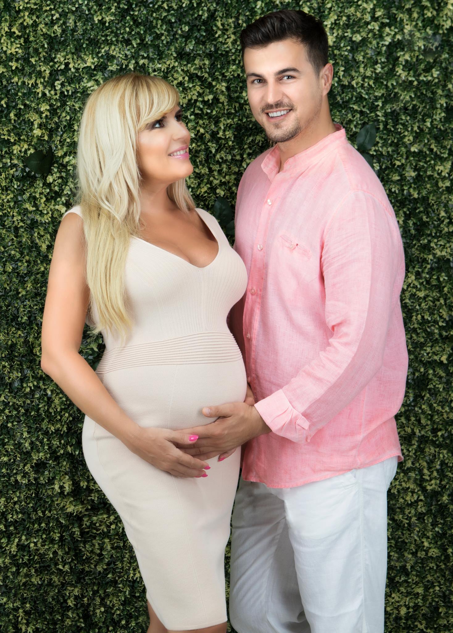 Elena Udrea însărcinată, îmbrăcată într-o rochie mulată, în timp ce Adrian Alexandrov îi ținea mâna pe burtă