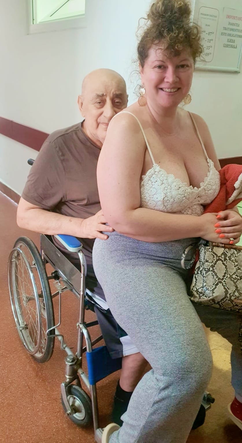 Viorel Lis în scaunul cu rotile la spital, în timp ce o ține în brațe pe Oana Lis, care l-a însoțit