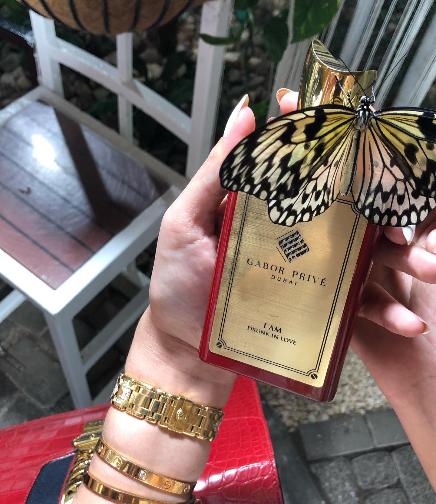 Parfumul I Am Drunk In Love creat de Ramona Gabor, ținut în mână chiar de ea, îl timp ce un fluture s-a așezat pe el