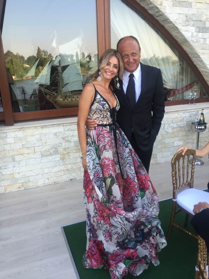 Diana și Dan Șucu, îmbrăcați elegant la un eveniment. Ea poartă o rochie cu bretele și imprimeuri florale, iar el un costum negru și o cămașă albă