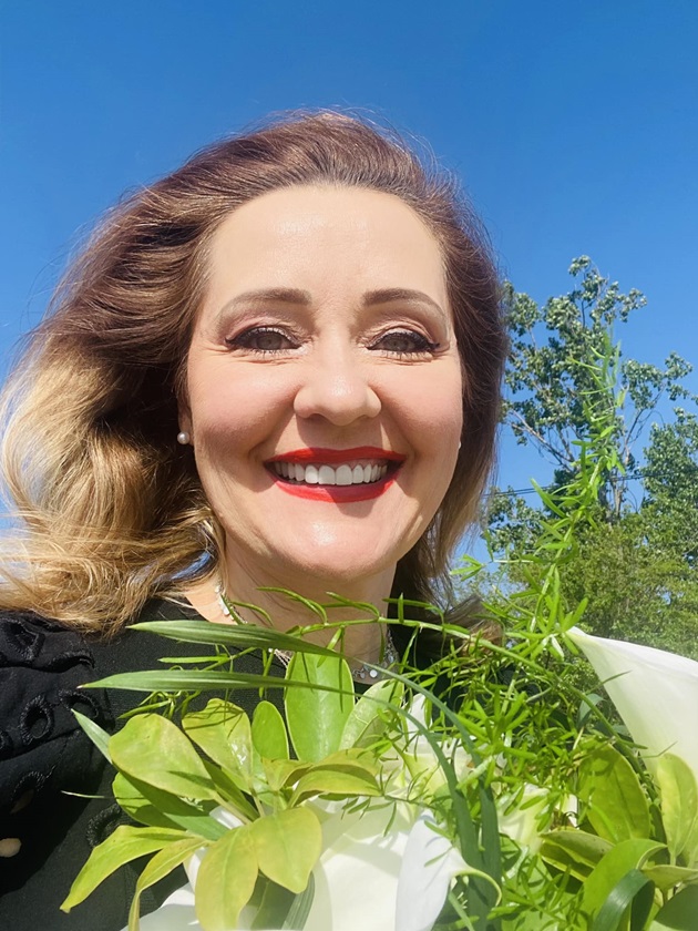 Elena Lasconi, primărița din Câmpulung Muscel, zâmbitoare, cu un buchet de flori în mână. 