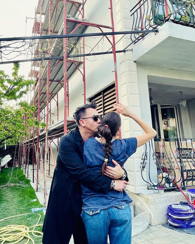 Răzvan Fodor o sărută pe obraz pe soția sa Irina Fodor, în timp ce fațada casei lor e în renovare