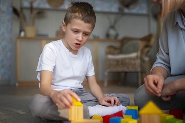 Mamă jucându-se pe covor cu fiul ei cu autism