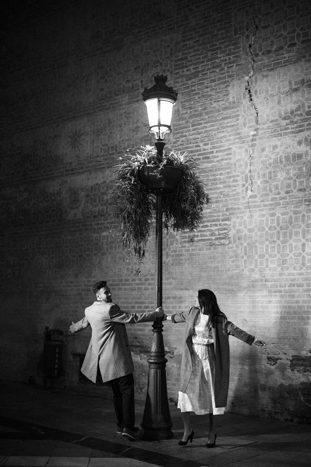 Imagine alb-negru cu parteneri care dansează în jurul unui stâlp de iluminat