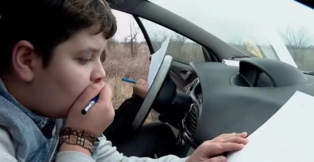 Unul dintre copiii familiei Moțoc, surprins în timp ce își face temele în mașină