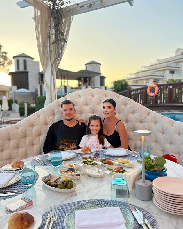 Andreea Tonciu pe terasa unui restaurant de lux alături de soțul ei și de fiica lor, luând masa lângă piscină