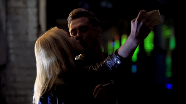 Parteneri care își fac un selfie în timp ce se sărută în întuneric