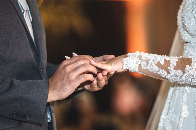 Bărbat care îi pune soției sale verigheta pe deget în ziua nunții