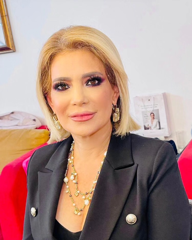 Cora Mizil într-un sacou negru, machiată profesional, cu gene false și bijuterii aurii
