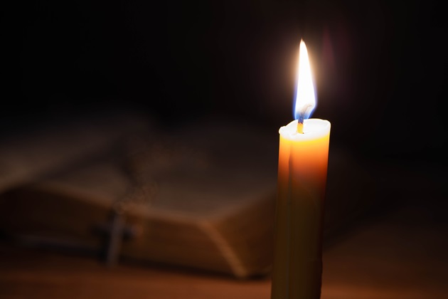 Lumânare care arde în fața unei biblii
