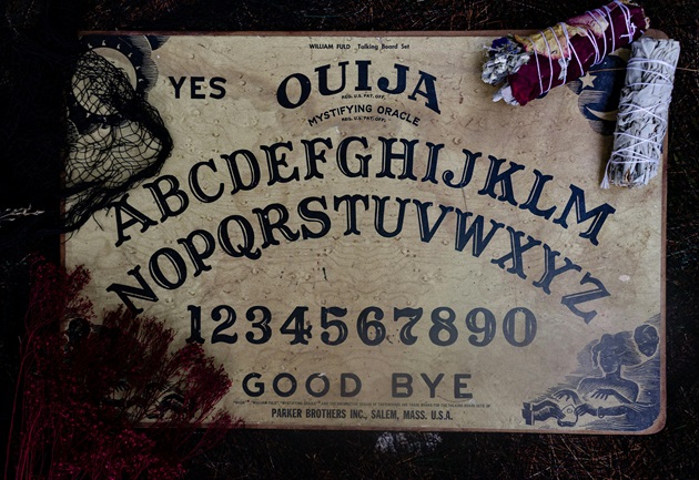 Placă Ouija peste care sunt așezate alte elemente utile în spiritism