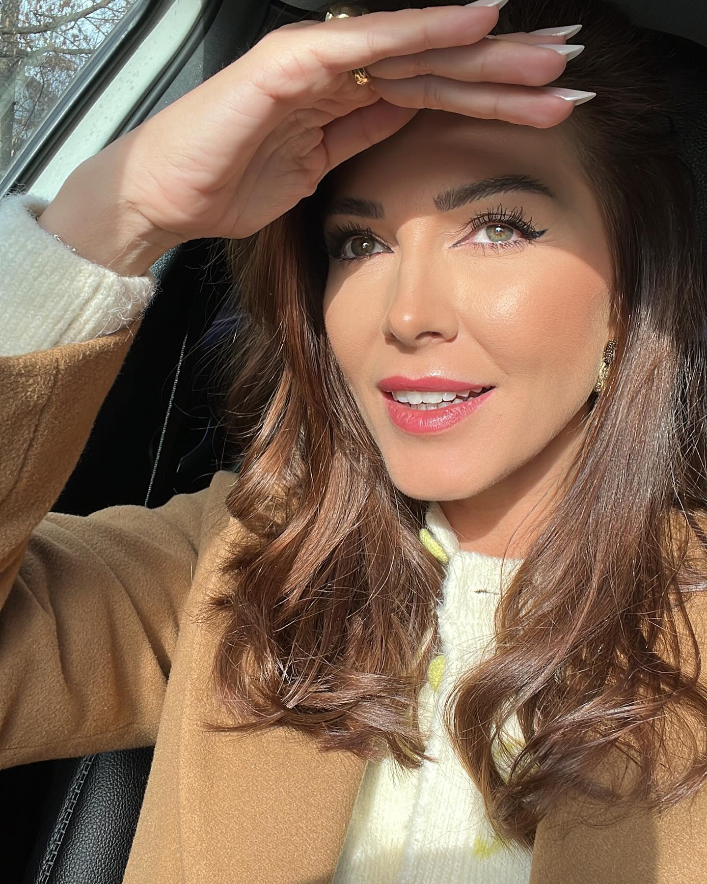 Ilinca Vandici în mașină, ținând mâna deasupra ochilor pentru a se proteja de soare