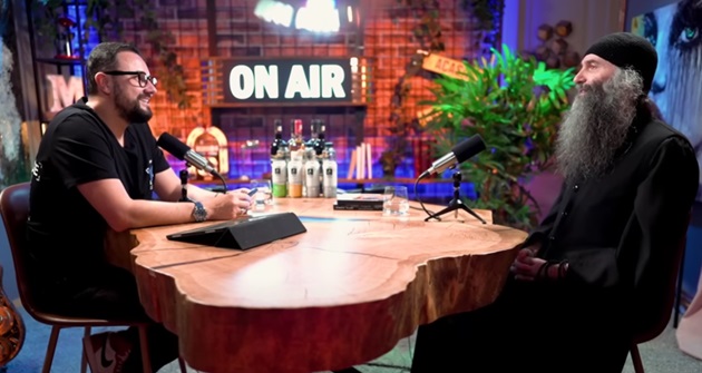 Cătălin Măruță și Părintele Pimen Vlad în camera în care se filmează podcastul „Acasă la Măruță”, stând de vorbă la aceeași masă