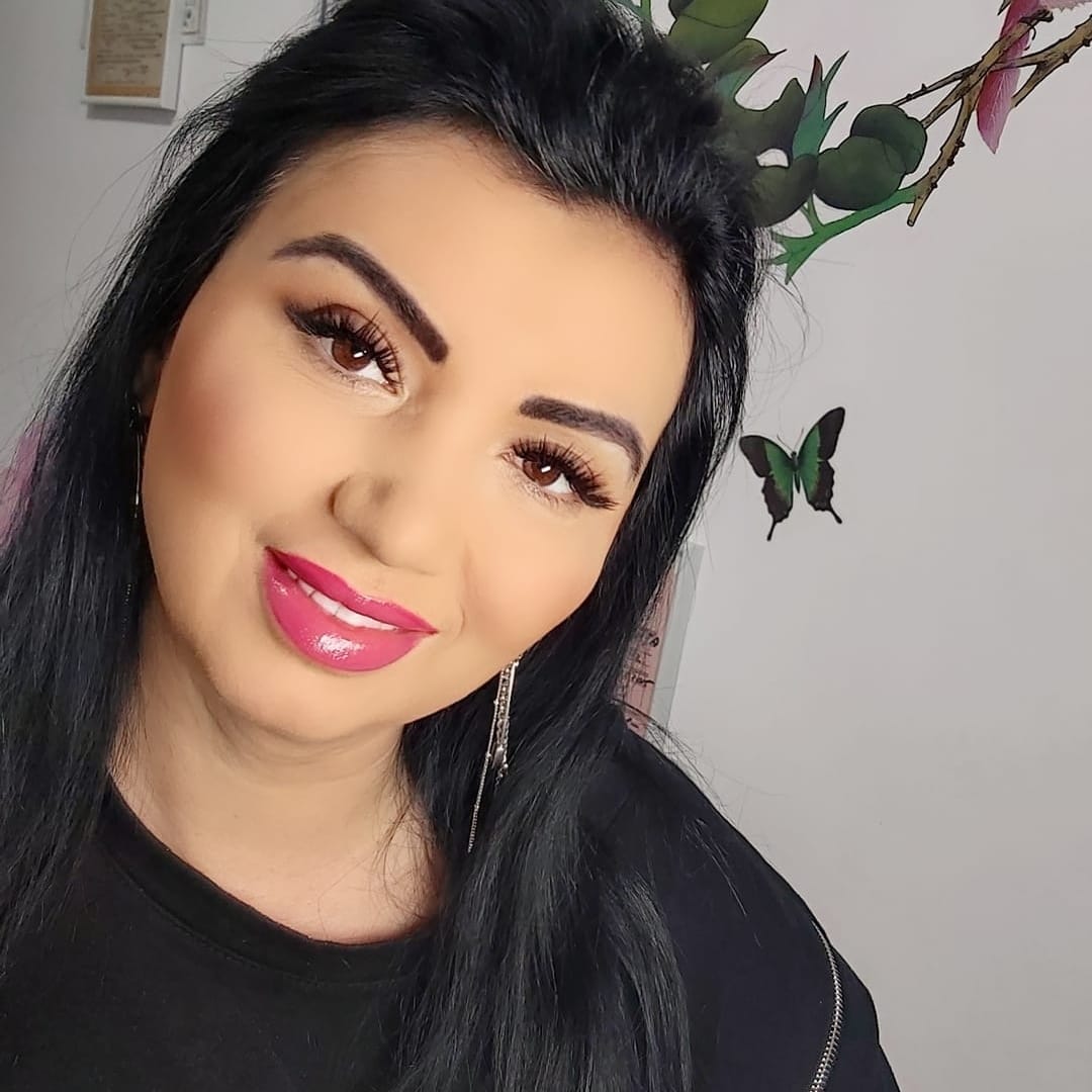 Adriana Bahmuțeanu zâmbitoare lângă un perete decorat cu fluturași, îmbrăcată în negru și purtând cercei lungi