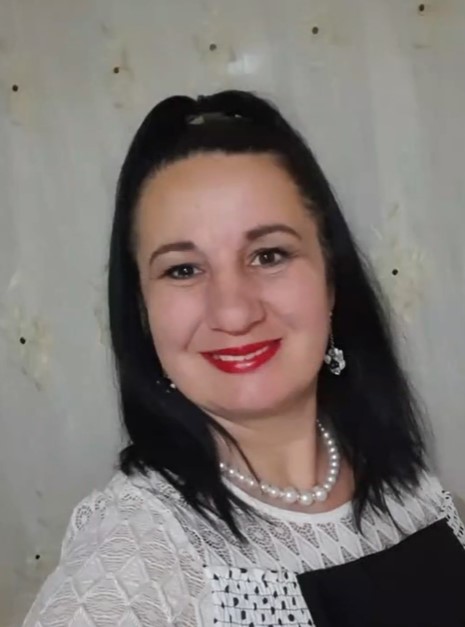 Maria Tănase zâmbitoare, cu părul prins în coadă, cu perle la gât și cu ruj roșu pe buze