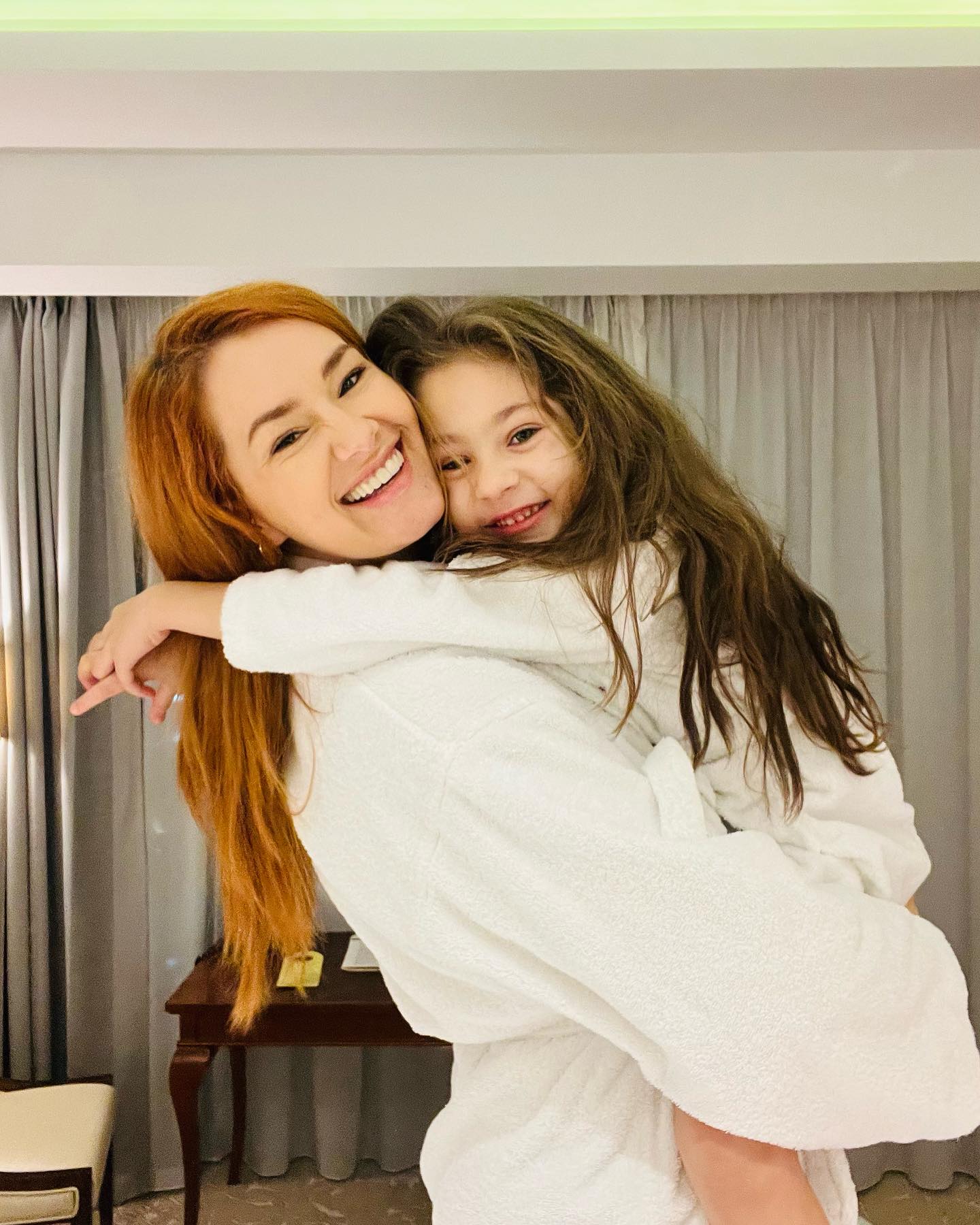 Feli Donose îmbrățișându-și fiica în camera de hotel, în timp ce amândouă erau îmbrăcate în halate albe