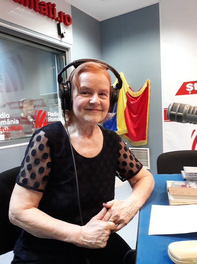 Lucia Moraru cu microfonul în față și căștile pe cap, în studioul Radio România Actualități