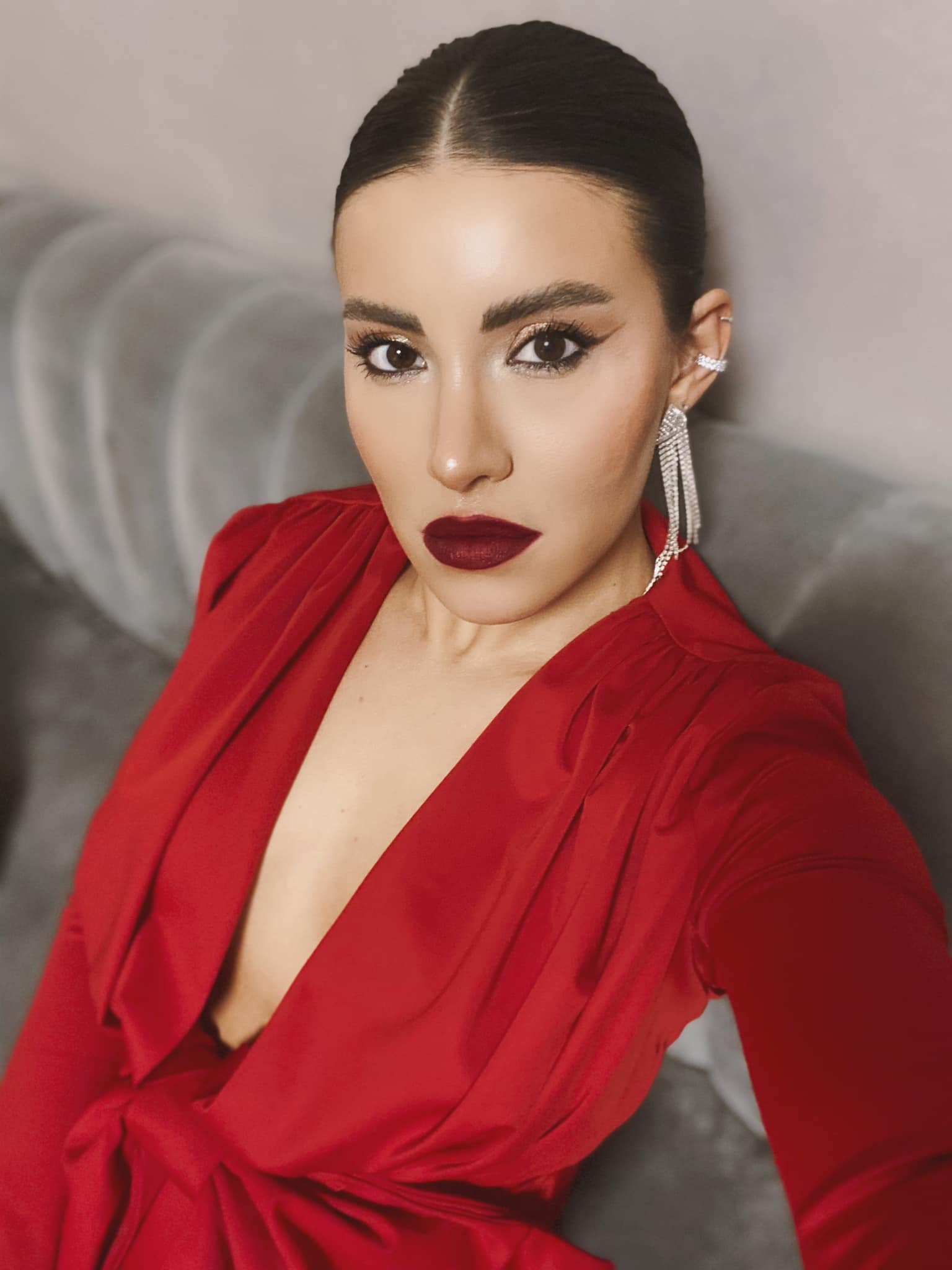 Nicoleta Nucă îmbrăcată într-o rochie roșie, stând pe o canapea gri