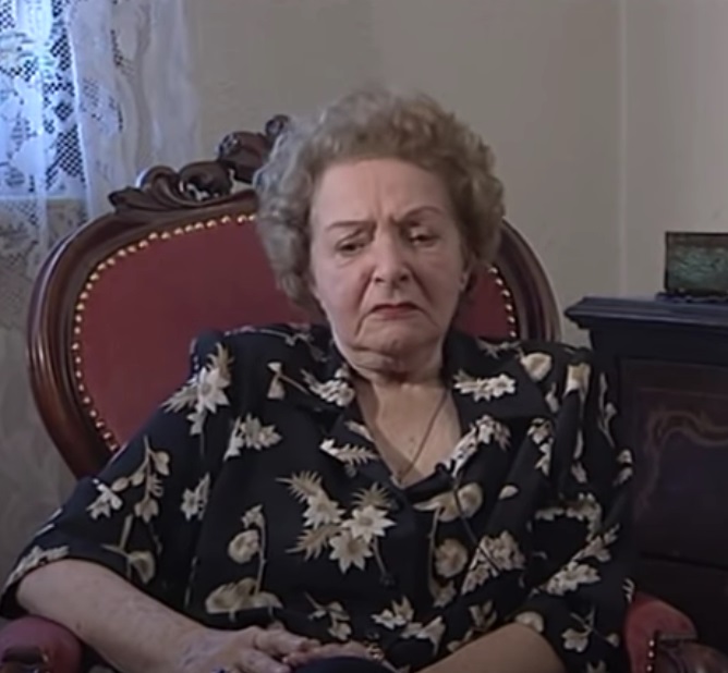 Dina Cocea în timpul unui interviu, îmbrăcată într-o bluză neagră cu flori, în timp ce avea părul grizonat