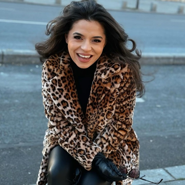 Eugenia Nicolae zâmbitoare, cu părul în vânt, îmbrăcată într-o haină cu animal print