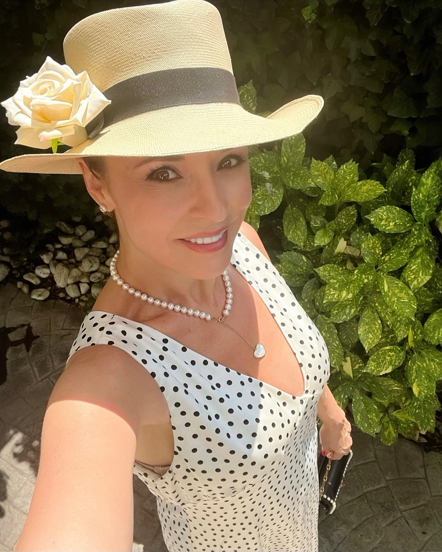 Andreea Marin într-o rochie albă cu buline negre, cu pălărie pe cap și perle la gât