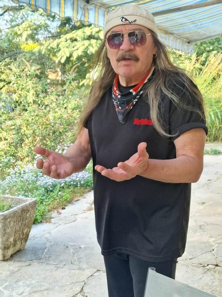Vasile Șeicaru stând cu mâinile întinse și cu ochelarii la ochi