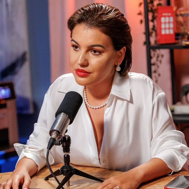 Romina Gingașu, într-o bluză albă, cu mărgele la gât, vorbind la microfon, în timpul podcastului „Acasă la Măruță”