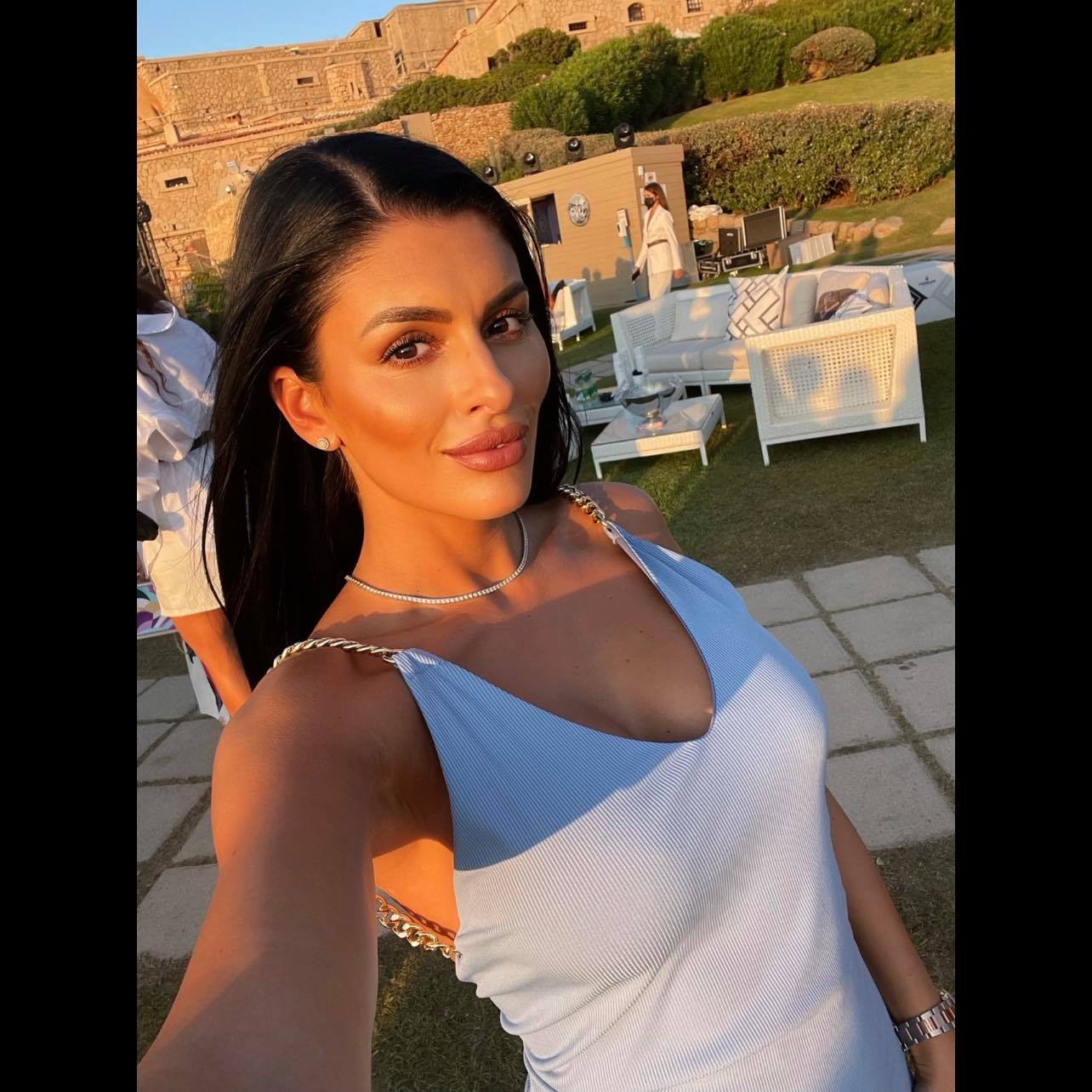 Elena Ardeleanu într-o rochie albă, cu bretele aurii, fotografiată în lumina apusului