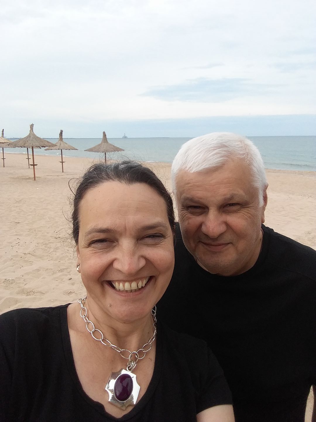 Ileana Șipoteanu și Dumitru Lupu zâmbitori, pe plajă, îmbrăcați în negru