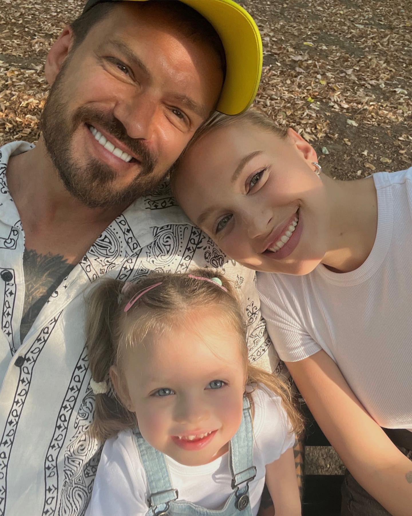Bogdan Vlădău și Gina Chirilă în parc, toamna, pe o bancă, alătui de fiica lor, Katia, afișându-și toți trei zâmbetul în fața camerei