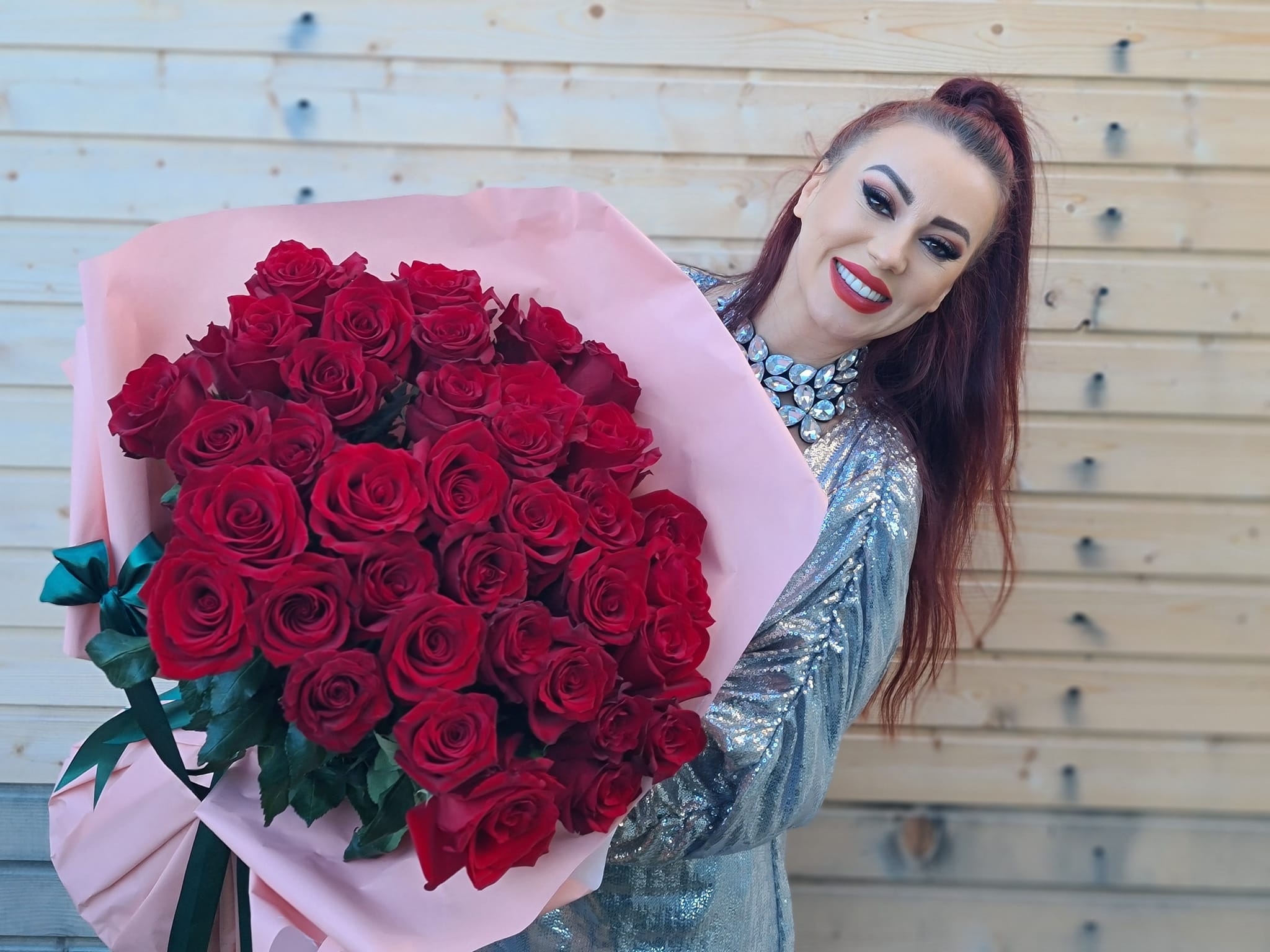 Larisa Drăgulescu fotografiată de ziua ei, ținând în brațe un buchet uriaș de trandafiri, în timp ce era îmbrăcată într-o rochie cu paiete