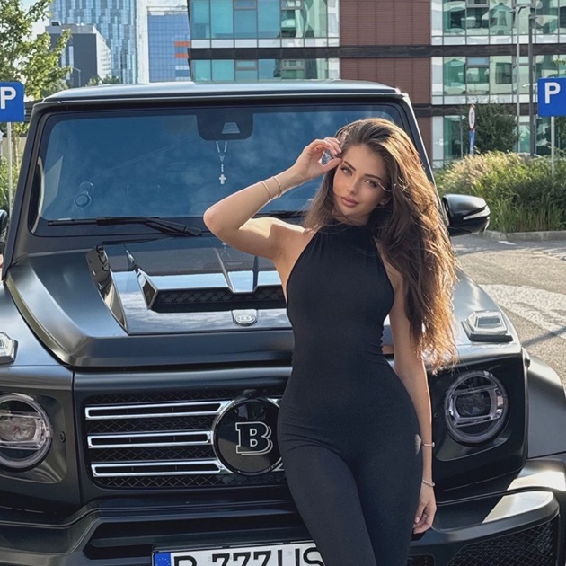 Andreea Bostănică își așază părul după ureche în timp ce stă sprijinită de noua ei mașină