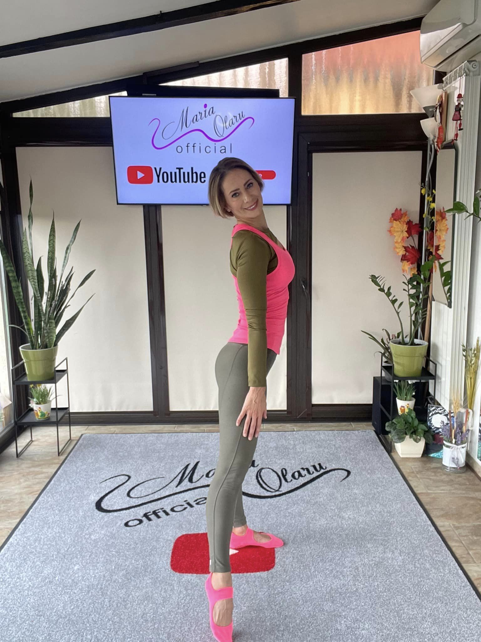 Maria Olaru stând pe un covor pe care este imprimat numele canalului său de Youtube