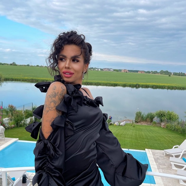 Cristina Rotaru pe balconul unui restaurant, îmbrăcată elegant, într-o rochie neagră, cu umeri goi